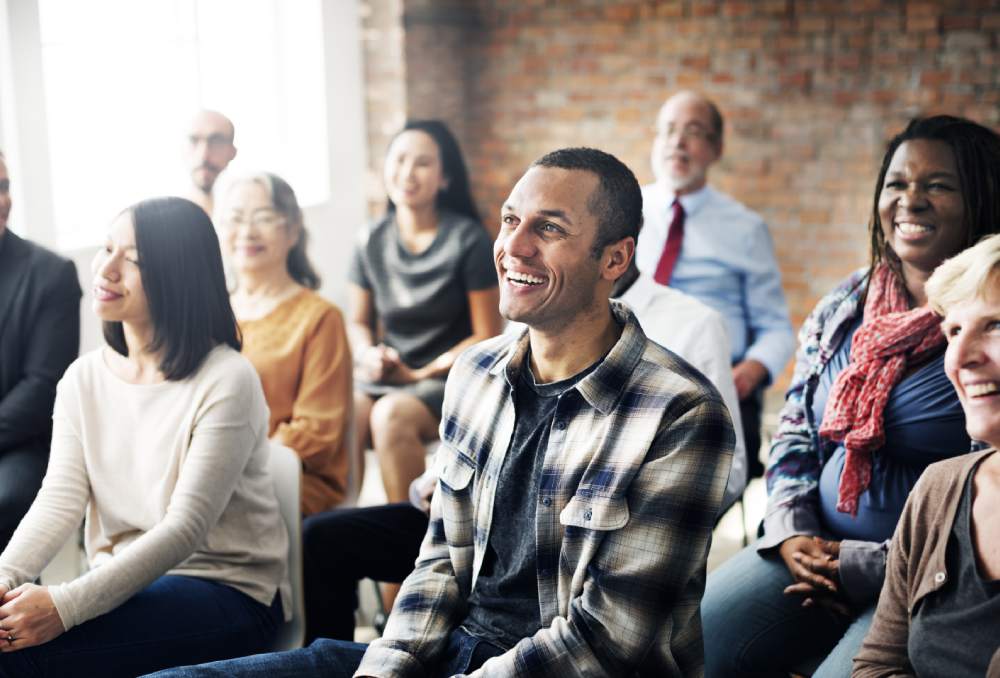 Northbrook college adult group of students in the classroom looking and smiling towards the teacher who is not in shot