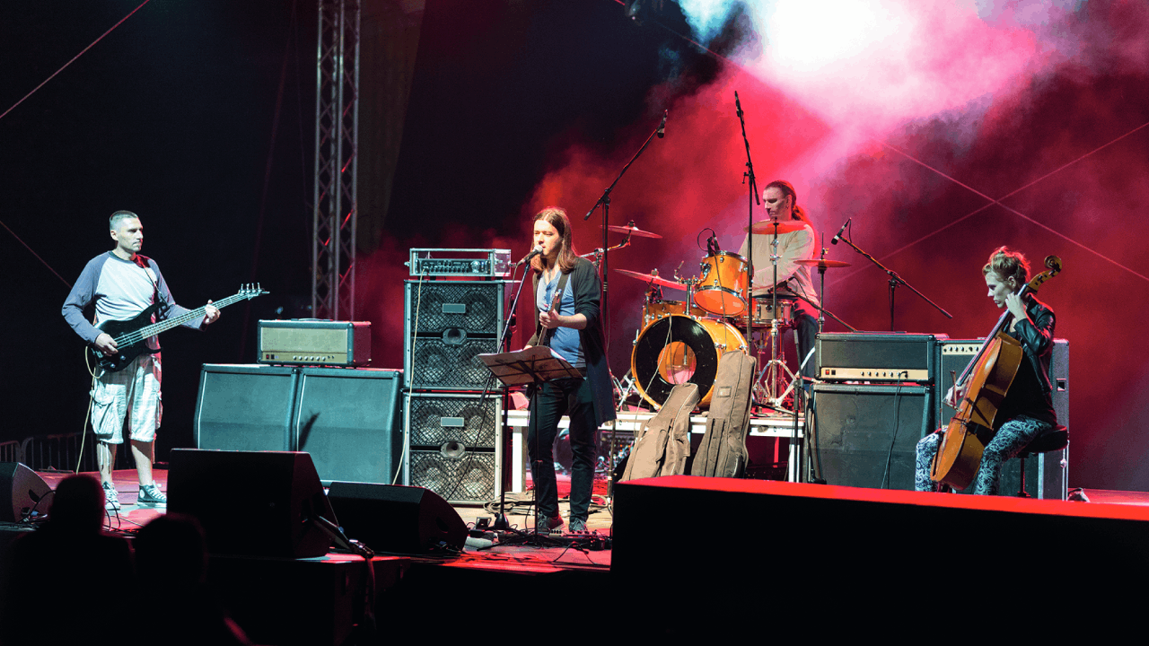 A band of four members playing live music on a stage with special lighting and smoke effects