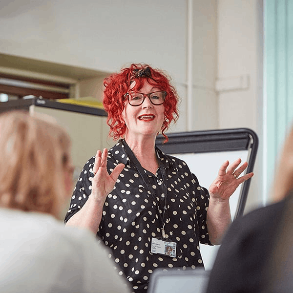 Northbrook College lecturer teaching in a classroom facing towards the camera with students facing the lecturer out of shot.
