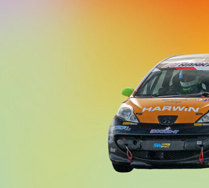 Image cut out on a multi-coloured background of a car with a person in a helmet inside.