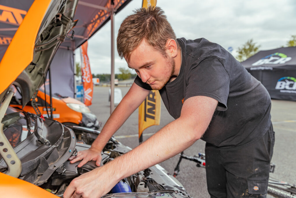 A student works on the engine of a motorsport car at an event